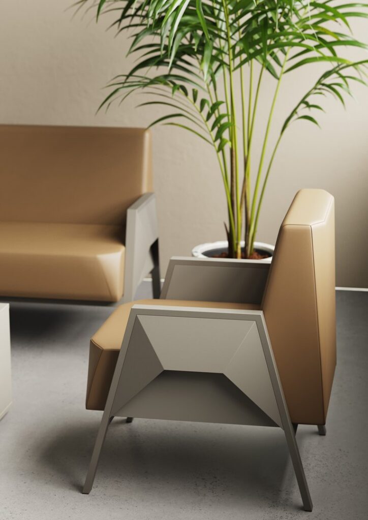 Fly — An office setting with a beige leather and grey metal armchair, a beige sofa in the background, and a green plant in a pot