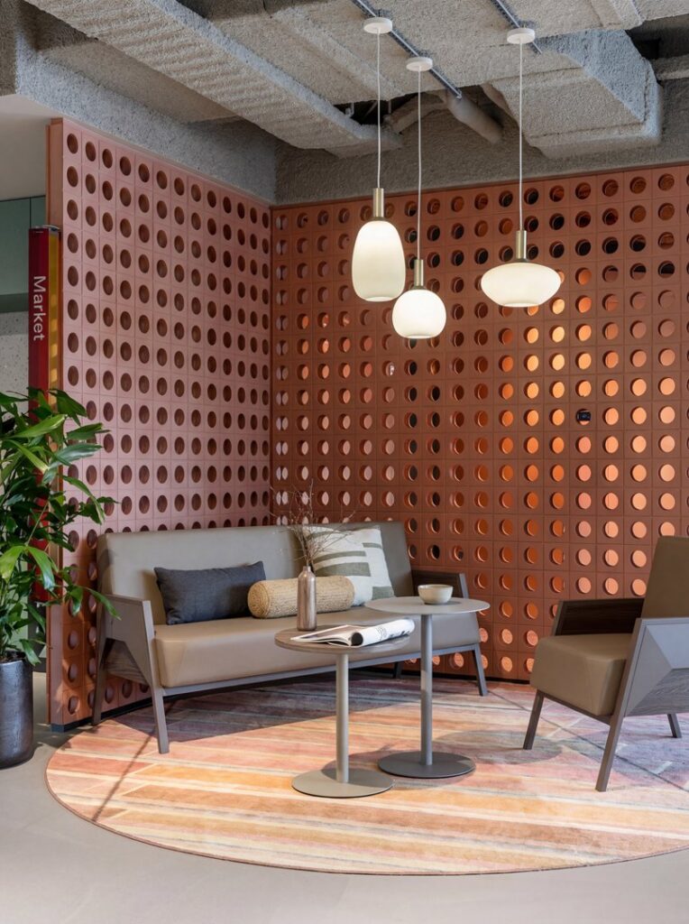 Fly — Lobby setting with a brown leather sofa and armchair set, two round side tables, a plant, and a patterned rug