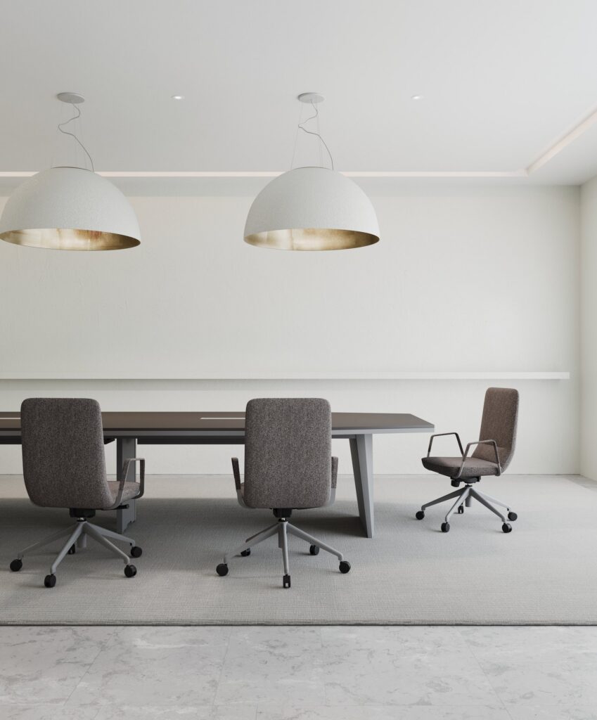 Loft — Gri döşemeli tekerlekli sandalyelerle modern bir ofis toplantı masası, beyaz duvarda iki büyük sarkıt lamba