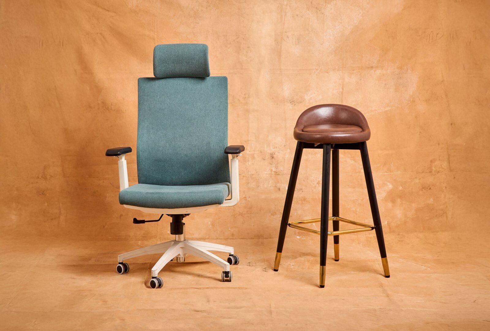 Stylish modern office chair and bar stool on a beige textured background, perfect for furniture design concepts.
