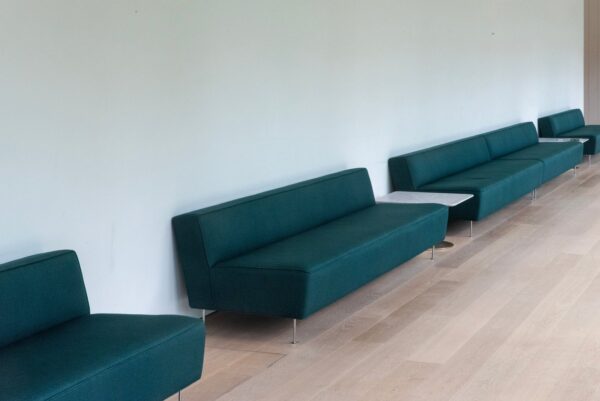 Sleek teal sofas in a modern waiting area with wooden flooring, perfect for contemporary interiors.